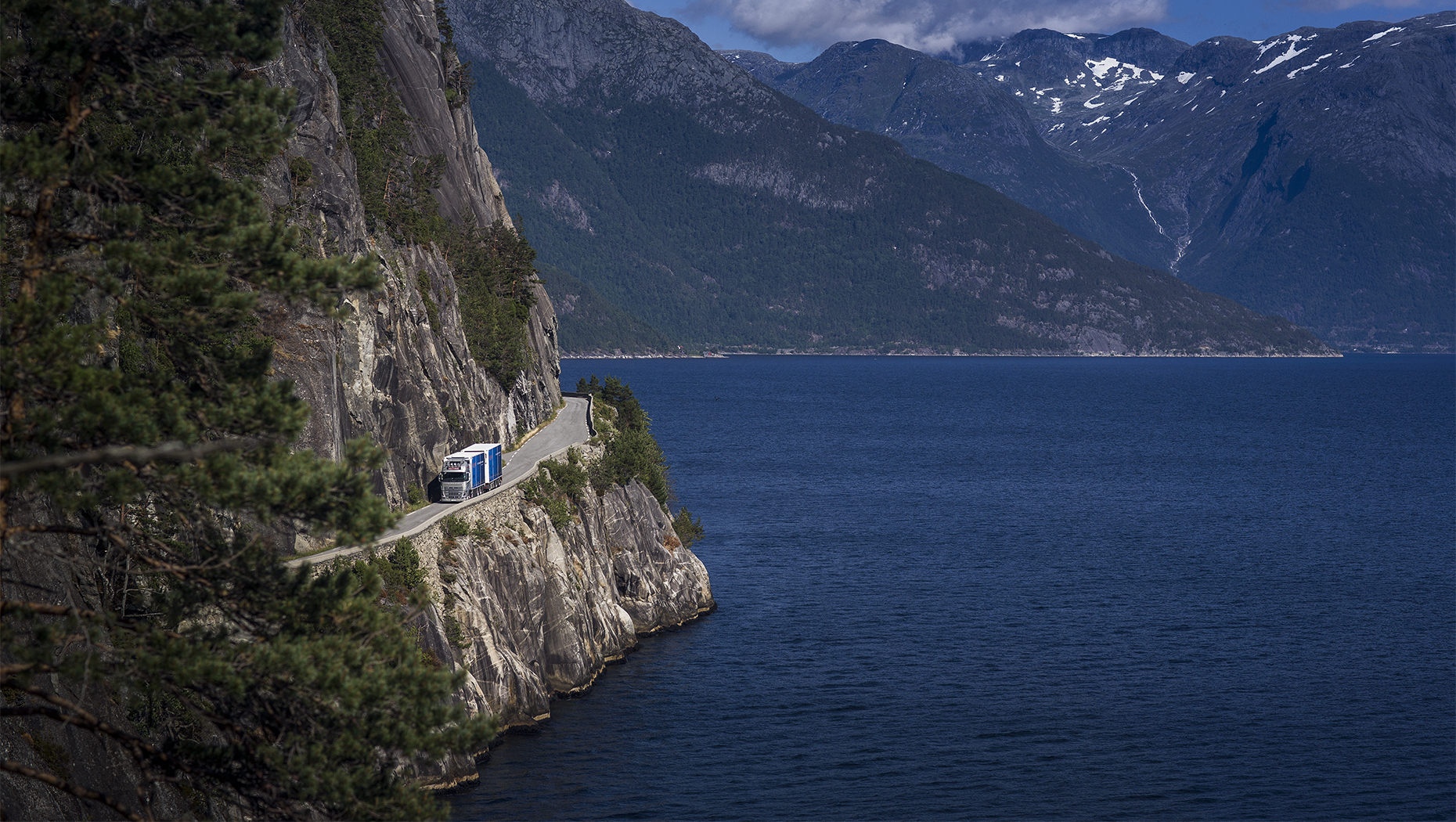 En lastbil på en vej langs en norsk fjord